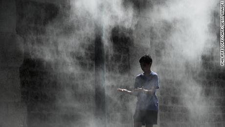 A boy cools off under a public water spray on the bank of the Seine river in Paris.