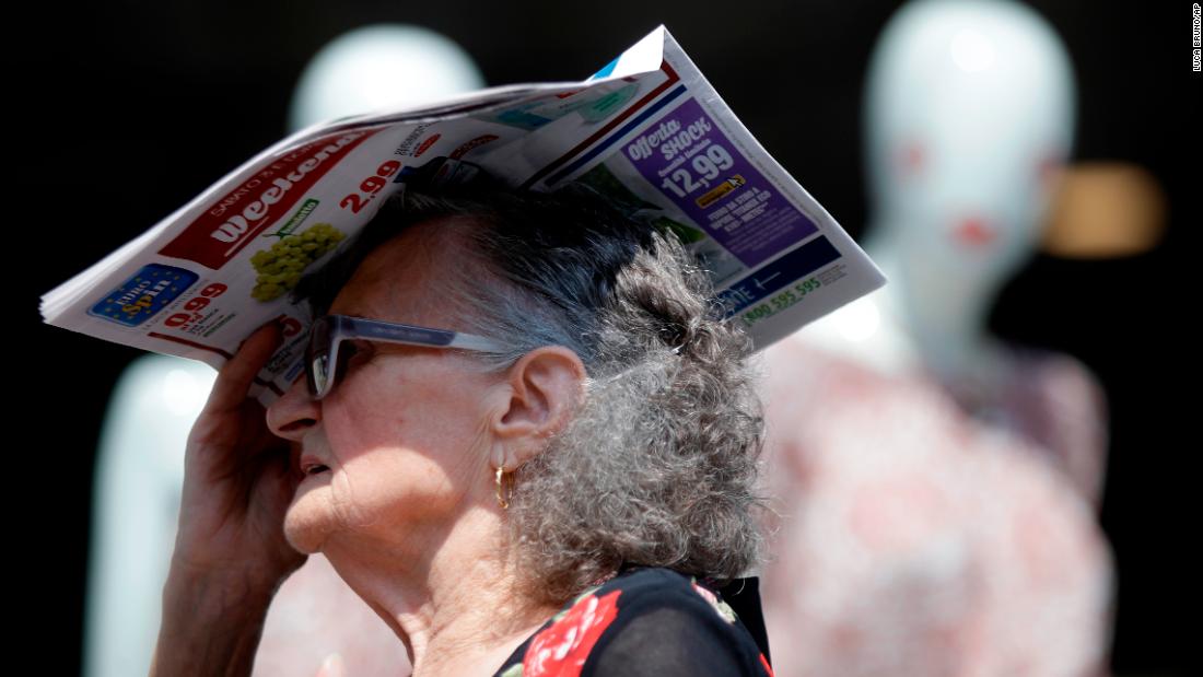 A woman shields herself with a newspaper in Milan, Italy, on Thursday, July 25.