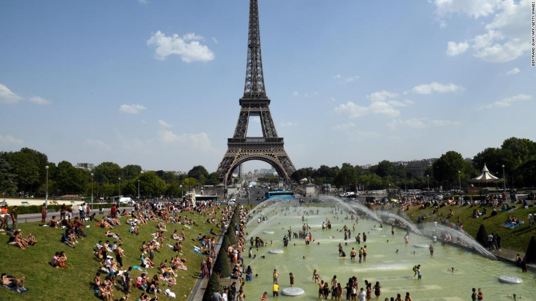 People cool off and sunbathe next to the Eiffel Tower in Paris on Thursday, July 25.