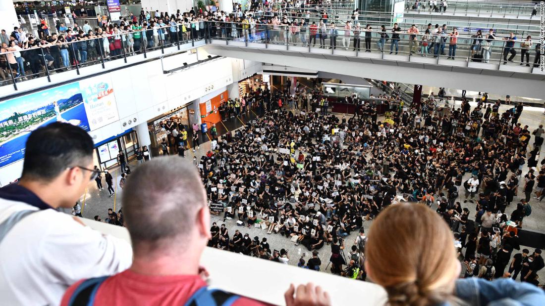 Travelers watch as protesters rally at Hong Kong's international airport on Friday, July 26.