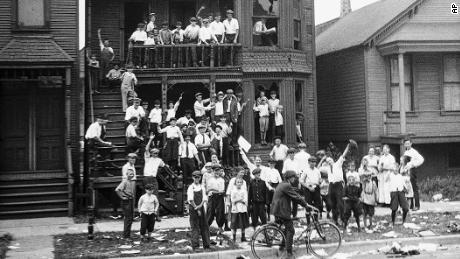 In this 1919 photo provided by the Chicago History Museum, a crowd gathers at a house that has been vandalized and looted during the race riots in Chicago. Some of the crowd is posing inside broken windows, others are standing on the lawn.