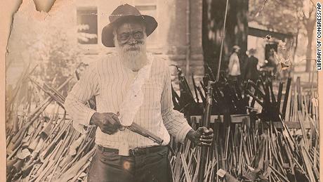 In this July 13, 1919 image provided by the Library of Congress, Daniel Hoskins stands with guns deposited at Gregg County Courthouse, in Longview, Texas, following race riots during Red Summer. 