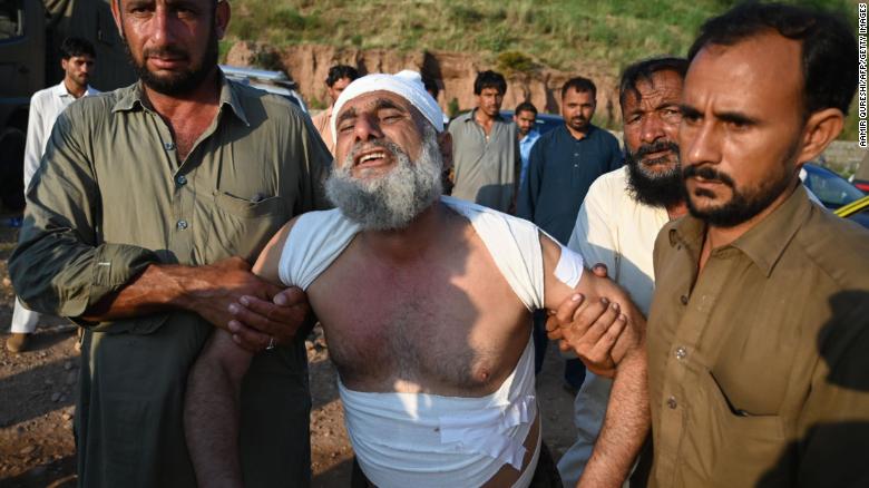 People assist a man at the scene where a Pakistani military aircraft crashed in Rawalpindi on July 30.