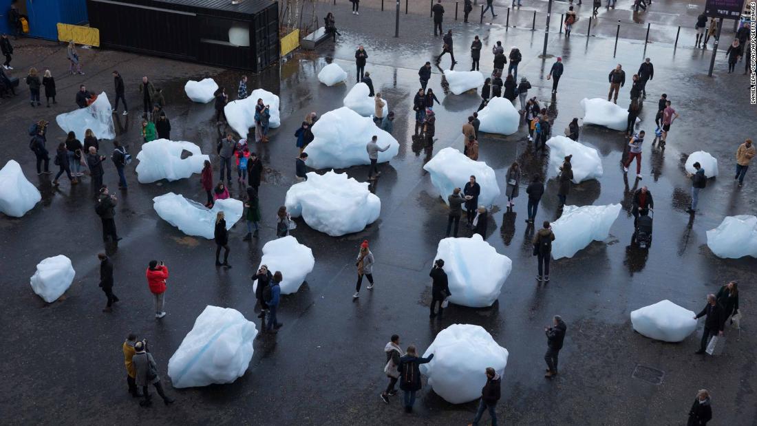 Visitors interact with blocks of melting ice from an exhibit called 'Ice Watch' in central London in December 2018.