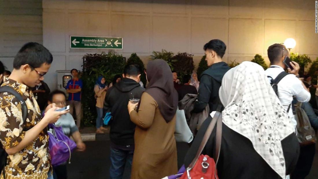 People stand outside after being evacuated following a strong earthquake in the area in Serpong, Banten province.