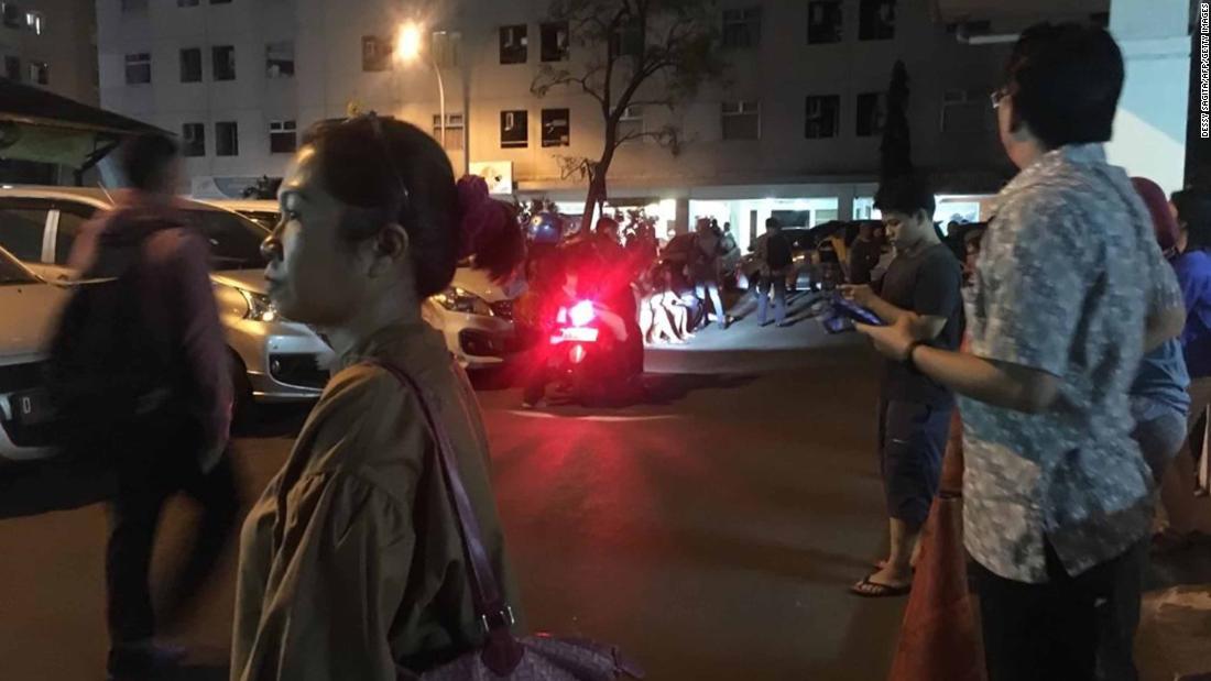 Residents stand outside an apartment block after a strong earthquake hit the area around Jakarta.