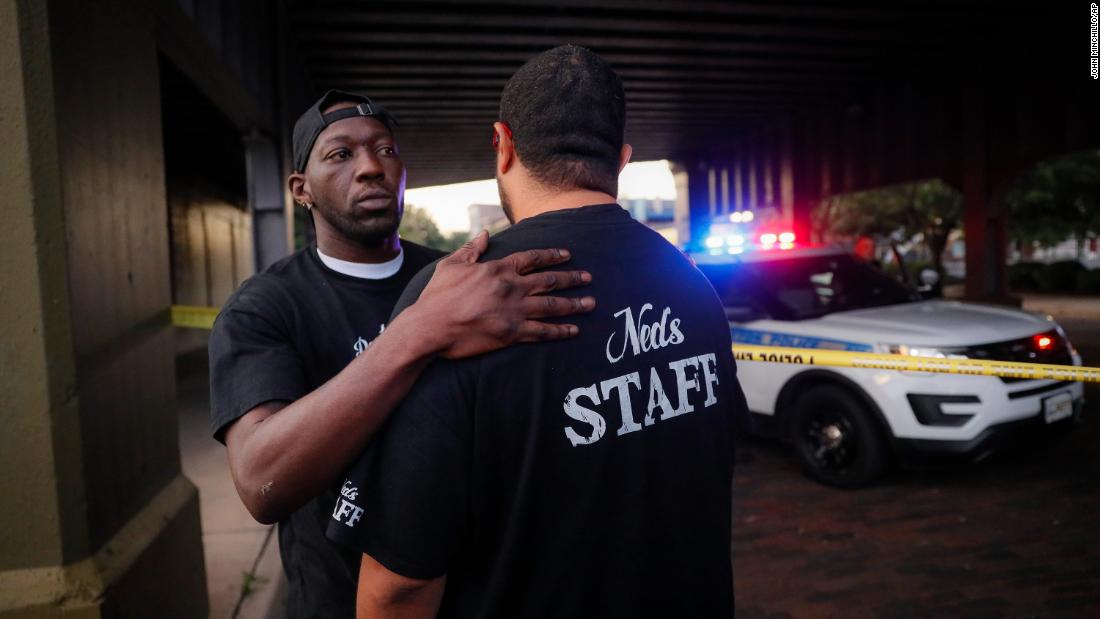 Witnesses comfort one another at the scene in Dayton on Sunday.