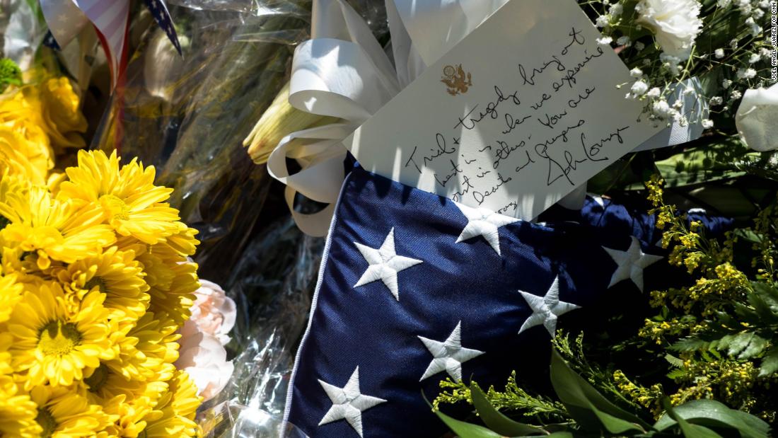 A flag and letter signed by US Sen. John Cornyn is seen on flowers at a makeshift memorial in El Paso.