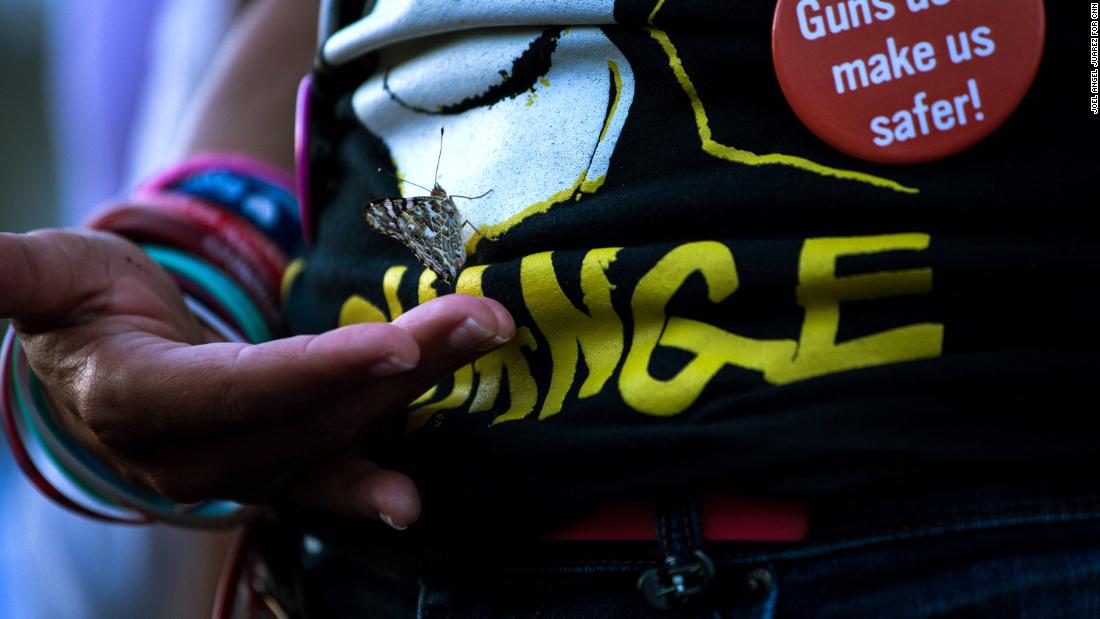 A butterfly grips onto Patricia Oliver during an El Paso vigil. Oliver's son, Joaquin, was killed in the Parkland, Florida, school shooting in 2018. Sunday would have been his 19th birthday.