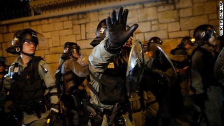 A riot policeman gestures to photographers as they retreat back to Kwun tong police station in Hong Kong, Sunday, August 4, 2019. 