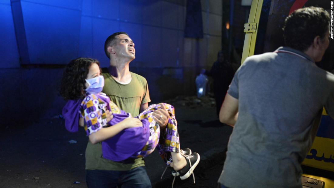 An Egyptian man carries a young cancer patient out of the National Cancer Institute.