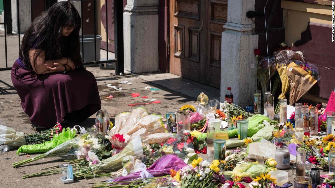 A woman kneels Monday at a memorial in Dayton, Ohio, where a mass shooting took place this weekend only hours after the shooting in El Paso.