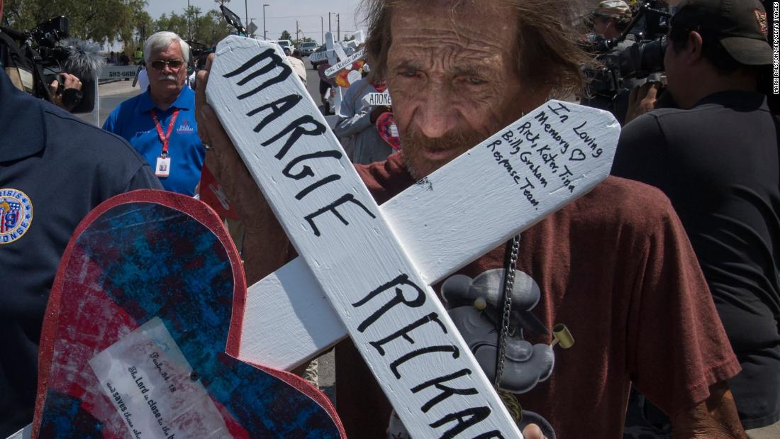 Antonio Basbo holds the cross of his common-law wife, Margie Reckard, who died in the shooting in El Paso.