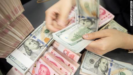 A Chinese bank employee counts 100-yuan notes and US dollar bills at a bank counter in Nantong in China&#39;s eastern Jiangsu province on August 6, 2019. - The Chinese currency steadied on August 6, a day after Beijing let the yuan weaken against the dollar, sending markets into freefall and leading the US to formally designate China a &quot;currency manipulator&quot;. (Photo by STR / AFP) / China OUT        (Photo credit should read STR/AFP/Getty Images)