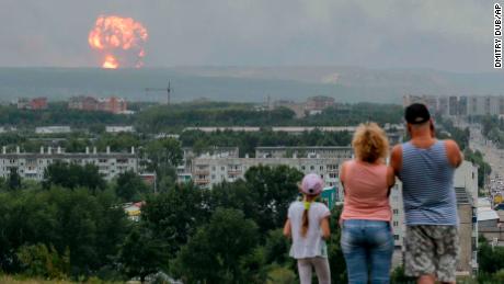 In this photo taken on Monday, Aug. 5, 2019, a family watches explosions at a military ammunition depot near the city of Achinsk in eastern Siberia's Krasnoyarsk region, in Achinsk, Russia.  Russian officials say powerful explosions at a military depot in Siberia left 12 people injured and one missing and forced over 16,500 people to leave their homes. (AP Photo/Dmitry Dub)
