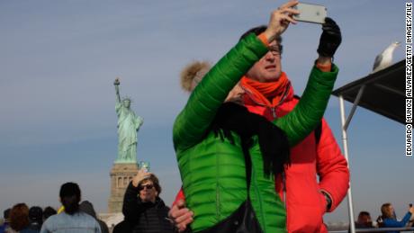 Tourists take pictures as a cruise passes the Statue of Liberty on January 21, 2018, in New York. 