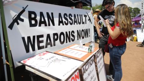 A &#39;Ban Assault Weapons Now&#39; sign is displayed near a voter registration table at a protest against President Trump&#39;s visit on August 7, 2019 in El Paso, Texas. 