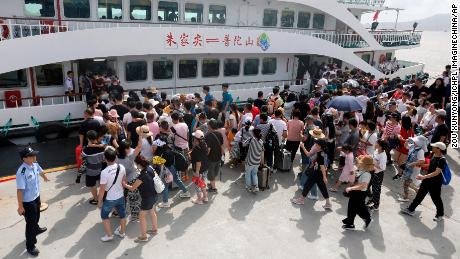 Chinese police officers evacuate tourists from a scenic spot in preparation for the Typhoon Lekima, the 9th typhoon of the year, in Zhoushan city, Ningbo city, east China&#39;s Zhejiang province, on August 8, 2019. 