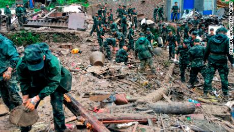 Rescuers look for survivors in the rubble of damaged buildings after a landslide in Yongjia.