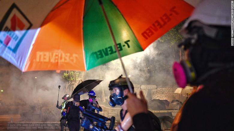 Protesters shield themselves from tear gas fired by the police.