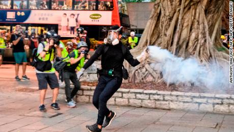 A protester in Hong Kong throws tear gas back at police amid scuffles in Tsim Sha Tsui, a major shopping district, on August 11, 2019. 