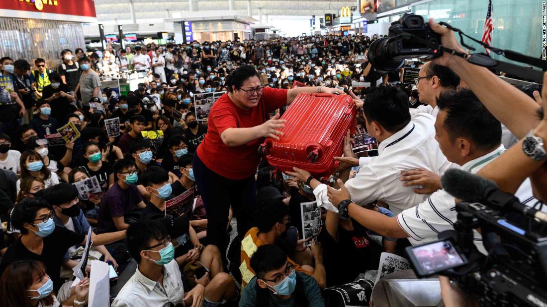 A traveler passes her luggage to security guards as she tries to enter the departures gate.