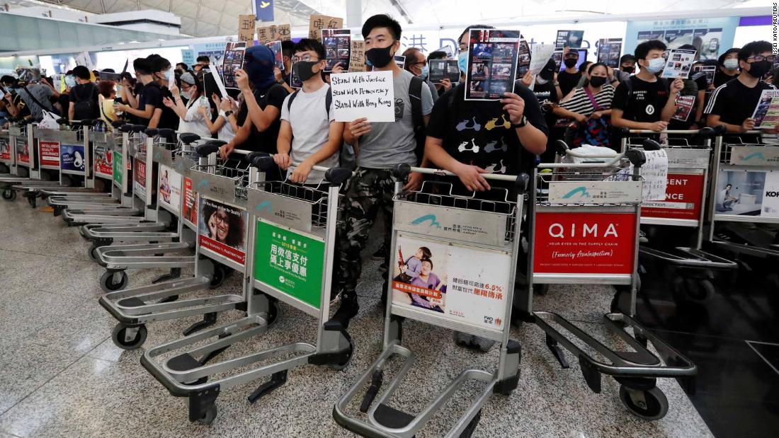 Anti-government protesters stand at a barricade made of luggage trolleys during a demonstration at the airport on August 13.