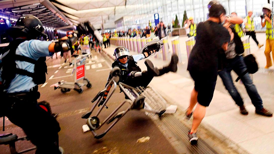 A police officer falls over an airport luggage trolley during a scuffle with pro-democracy protesters on Tuesday, August 13. For two days, <a href="https://www.cnn.com/2019/08/13/asia/hong-kong-airport-chaos-intl-hnk/index.html" target="_blank">protesters flooded the airport.</a> Check-ins were suspended and dozens of outgoing flights were canceled.