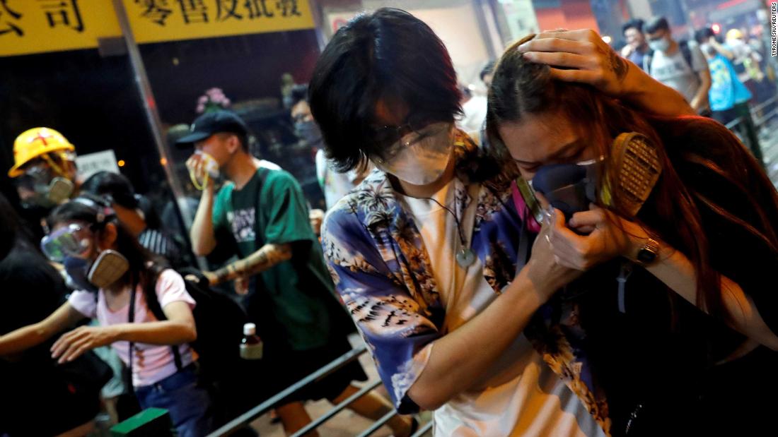 Protesters react after police fired tear gas to disperse a demonstration at the Sham Shui Po police station in Hong Kong on Wednesday, August 14.