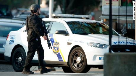 A police officer patrols the block near a house as they investigate an active shooting situation. 