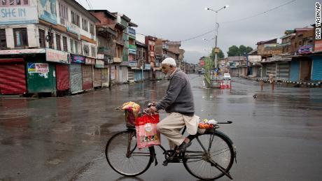 A Kashmiri man rides a bicycle through a deserted street during security lockdown in Srinagar, Indian-controlled Kashmir, on August 14, 2019.