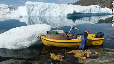 Inuit fishermen prepare a net as free-floating ice floats behind at the mouth of the Ilulissat Icefjord.