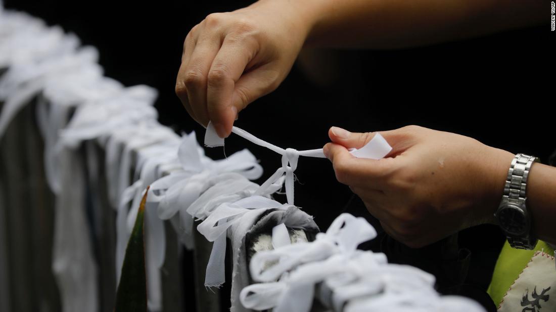 A protester ties a white ribbon, symbolizing the pure intentions of young protesters, during a march organized by teachers in Hong Kong on August 17.