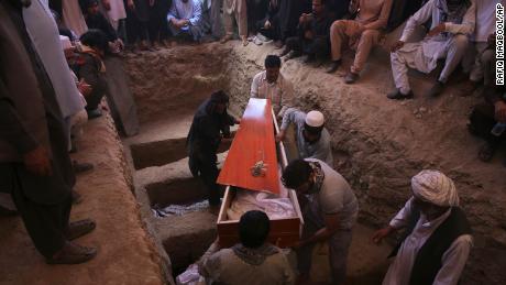 Afghans carry the body of a victim of a wedding hall bombing during a mass funeral in Kabul.