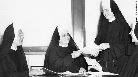 Sister Jean (second from right) looks over paperwork in a vintage photo of her.