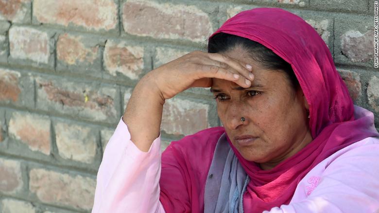 An Indian Kashmiri woman waits outside a police station after her relative was detained during night raids in Srinagar on August 20, 2019. 