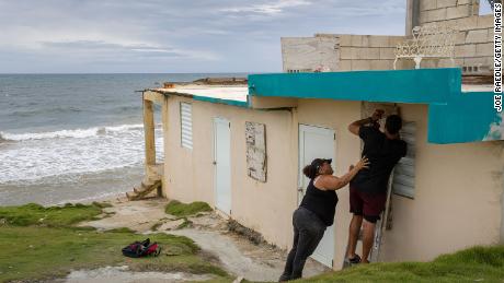 Ya Mary Morales (L) and Henry Sustache put plywood over the windows of their home as they prepare for the arrival of Tropical Storm Dorian.