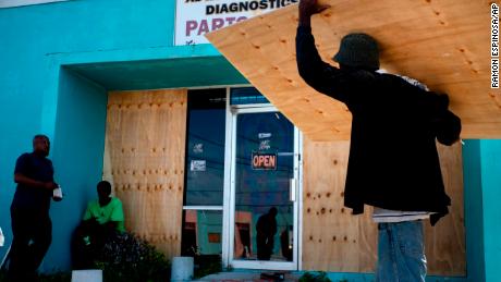 Workers board up a shop&#39;s window front as they make preparations for the arrival of Hurricane Dorian, in Freeport, Bahamas.