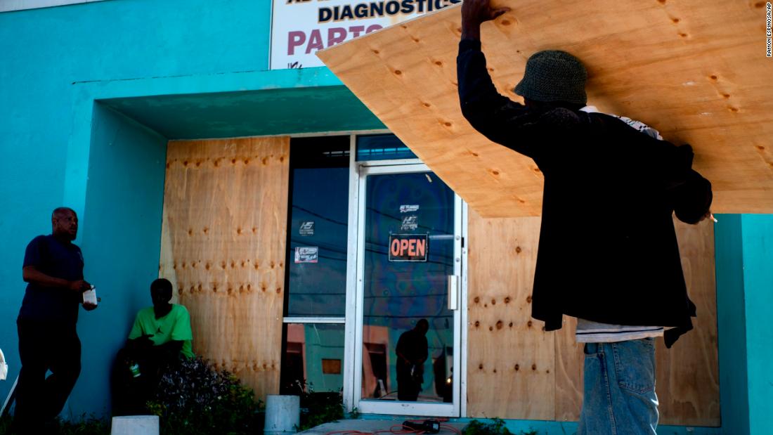 Workers board up a shop's window front as they make preparations for the arrival of Hurricane Dorian in Freeport on August 30.