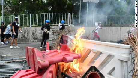 A flight attendant sprints past a burning barricade in Tung Chung on the way to Hong Kong international airport.