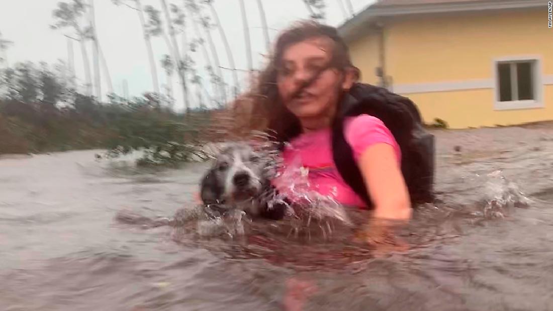 Julia Aylen carries her dog as she wades through waist-deep water near her home in Freeport on September 3.