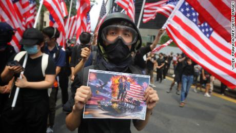 A man holds a placard as protesters wave US national flags while they march from Chater Garden to the US consulate in Hong Kong on September 8.