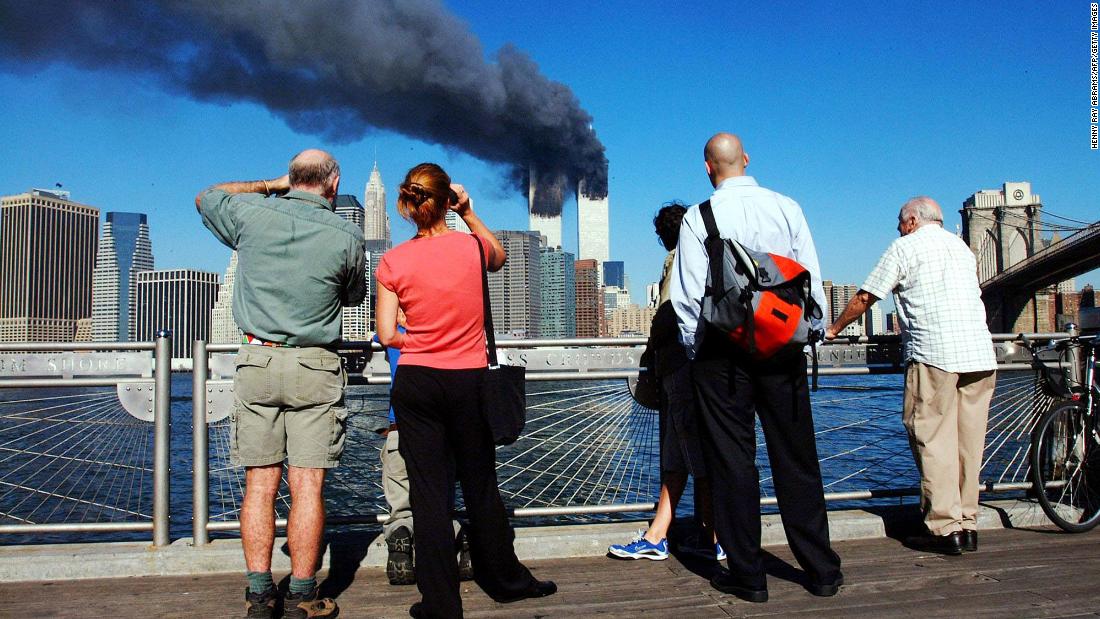 Pedestrians look across the East River to the burning towers.