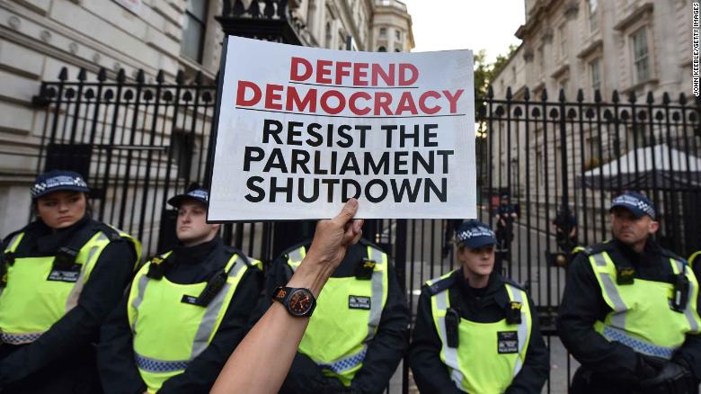 A protester holds a placard at the gates of Downing Street during a demonstration against the UK Government&#39;s decision to  prorogue parliament.