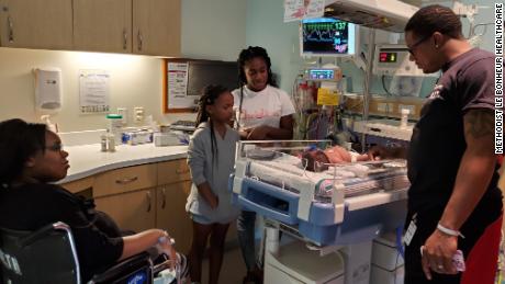 Parents Cametrione Malone-Brown and Justin Brown and big sisters Ameriyah Moore, right, and Ahjeah Moore look down at baby Christina.