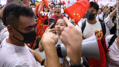 Pro-Beijing counter protesters wave Chinese flags to pro-democracy demonstrators gathering in Yuen Long MTR subway station to attend a singing rally of &#39;Glory to Hong Kong&#39; in a shopping mall in Hong Kong on September 12, 2019. 