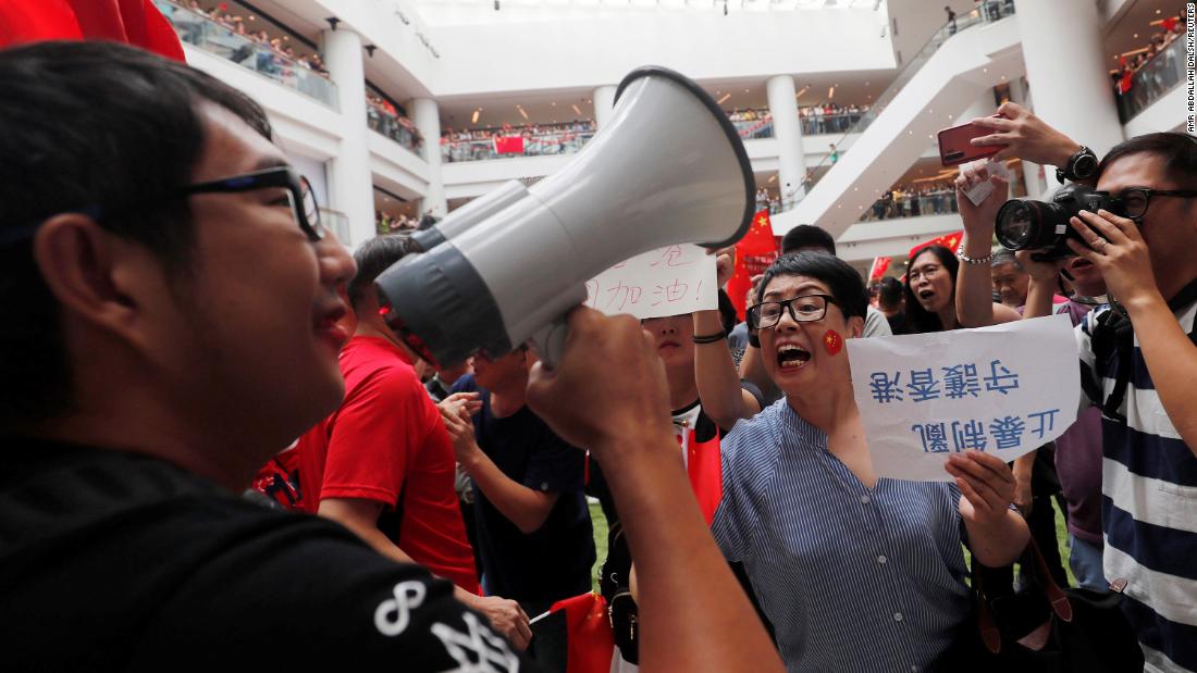 Pro-government and anti-government supporters chant against one another at a shopping mall in Hong Kong on Friday, September 13. The sign translates to &quot;Stop violence and curb chaos; safeguard Hong Kong.&quot;