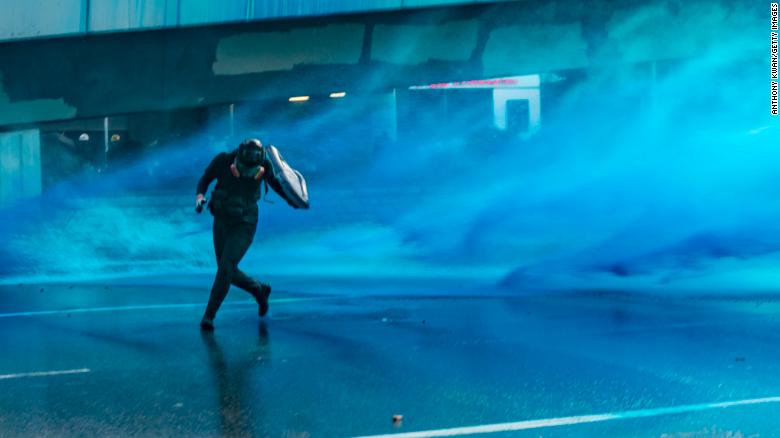 Pro-democracy protesters react as police fire water cannons at them outside the Central Government Complex on September 15, 2019 in Hong Kong.