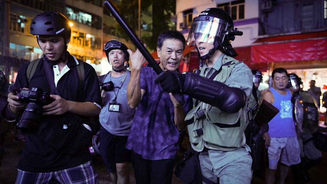 A pro-China supporter, center, is escorted by police after confronting journalists in Hong Kong, on September 15.