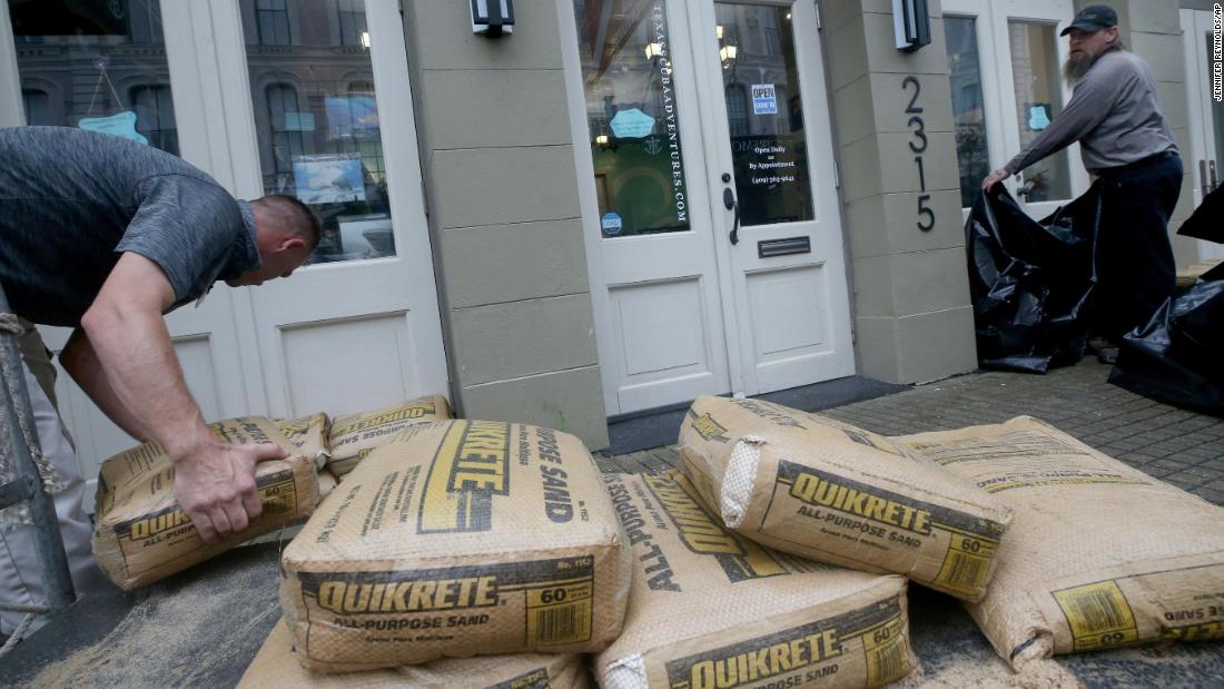 Jeremy Franklin, left, with Mitchell Historic Properties, unloads bags of sand at Texas Scuba Adventures, in Galveston, Texas.